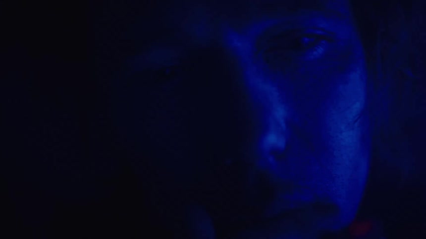 Mans face illuminated by deep blue light