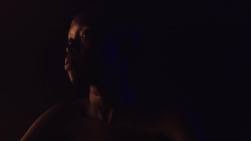 A black lady looking around while standing in a dark room