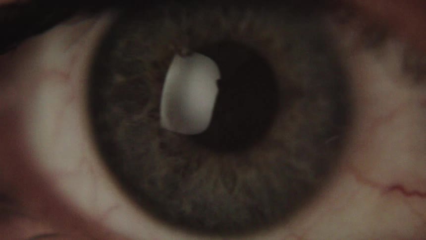 A person blinks once revealing a green eyelid