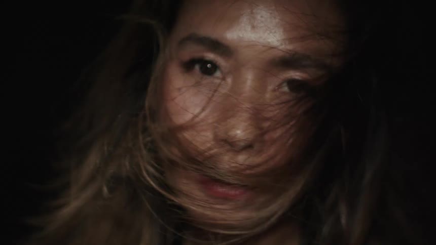 The video shows a dark scene and in the first second a persons face is dimly lit with a yellow light the scene then goes completely dark for the rest of the clip