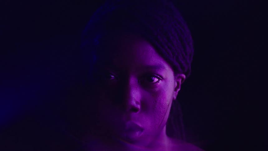 Female face highlighted by intense purple lighting