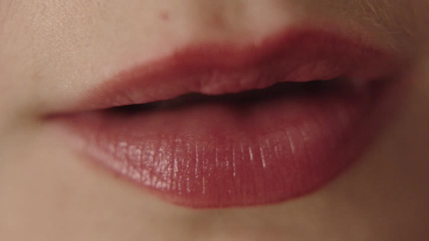 A very close view of a persons mouth shows the lips moving as if talking