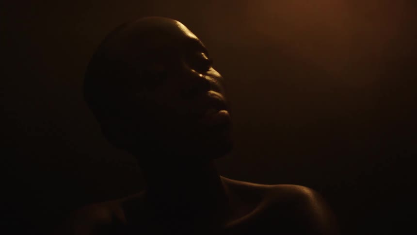 Bald person in side silhouette lit by purple light