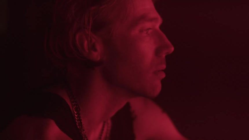 Man smokes a cigarette under intense red lighting