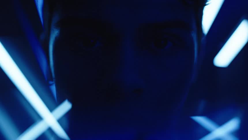 Shadowed face in closeup surrounded by blue light beams