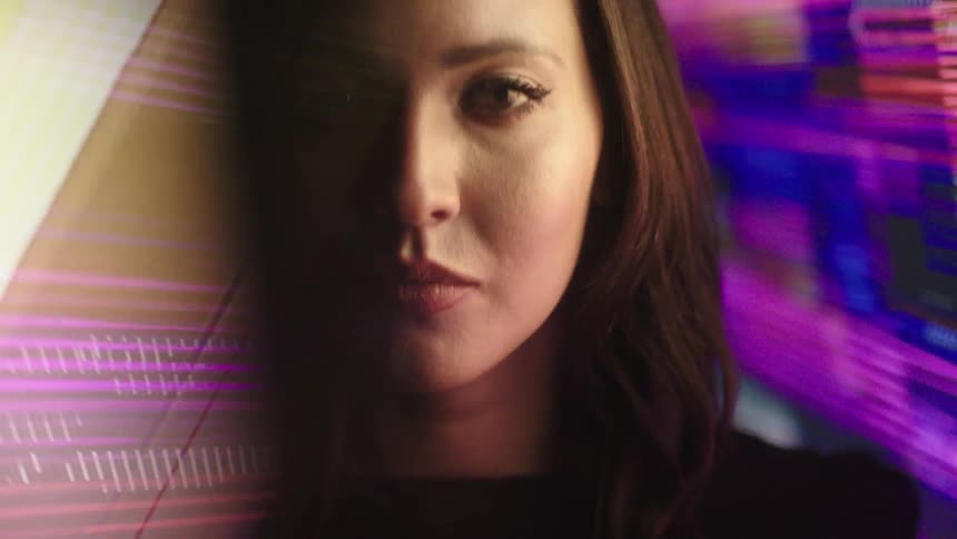 Womans face illuminated by blue and purple light in a dark setting