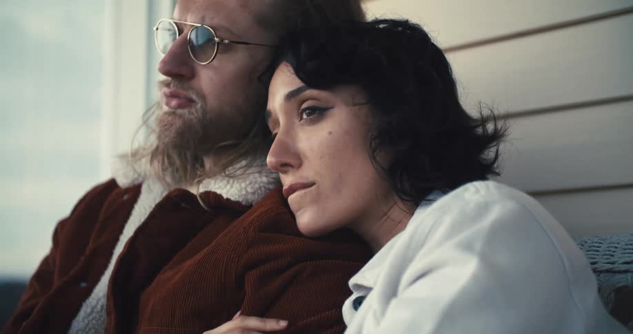 Close up portrait of a young woman hugging her partner tightly as the both sit on a chair outdoors during daytime