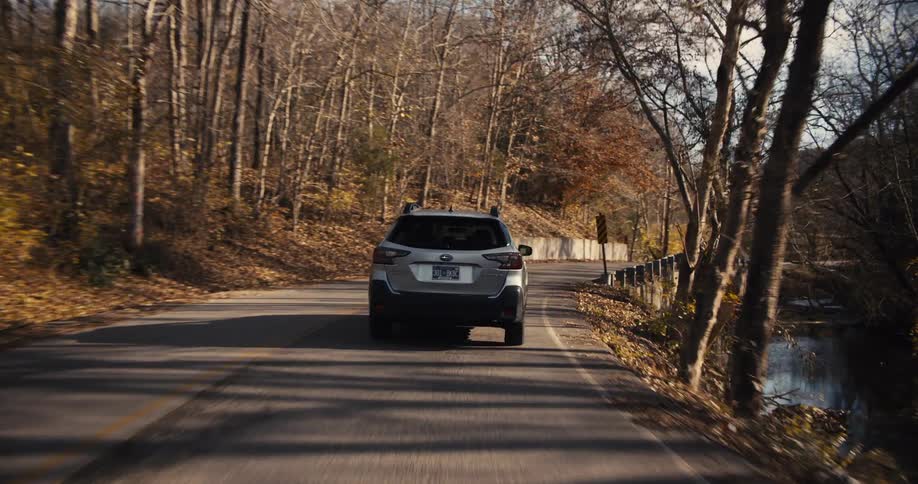 Car traveling on woodland road along a shallow creek