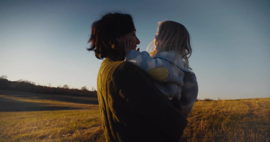 A mother and child play together in a sunlit field