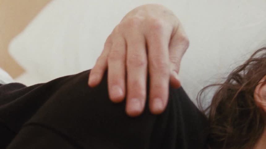 A womans shoulder is being rubbed in bed