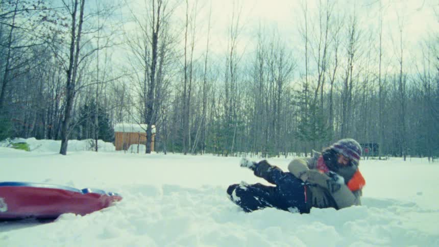 A mother plays around in the snow with her son