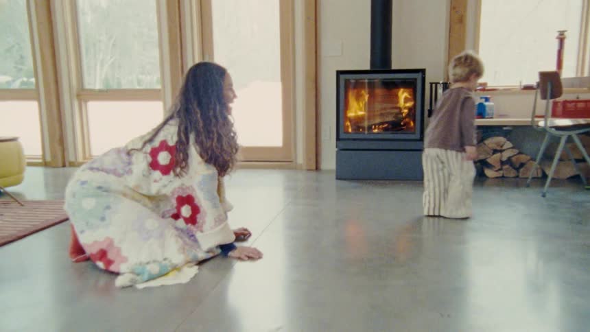 A woman on the floor of her home pointing and telling a boy to fetch something