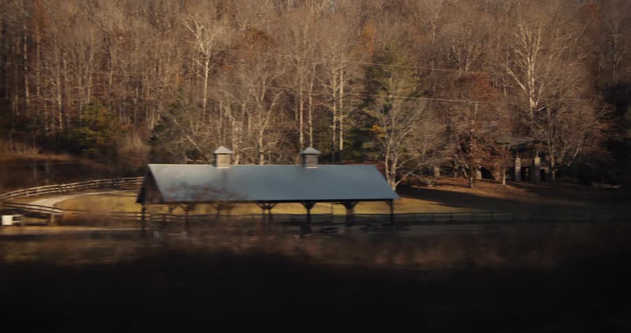 A highway passes through a rural community surrounded by leafless trees at midday