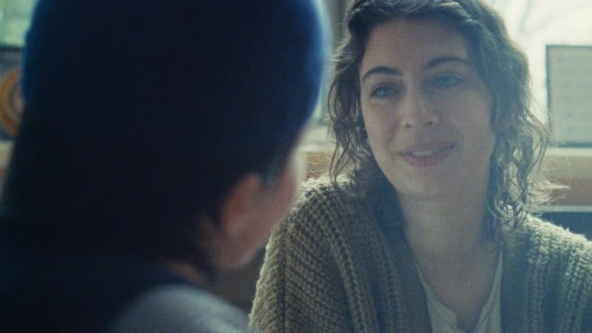 Woman smiles warmly while talking to someone in a bright setting