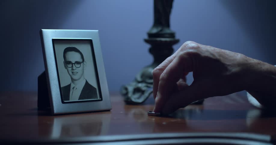Elderly hand picks up a ring on a table next to a picture frame