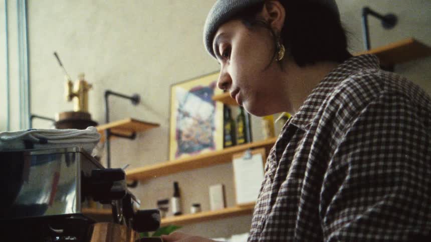 A barista prepares coffee at an espresso machine in a cafe