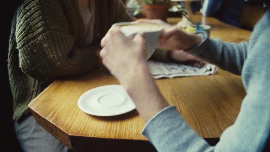 Two people sit at a cafe table enjoying coffee together