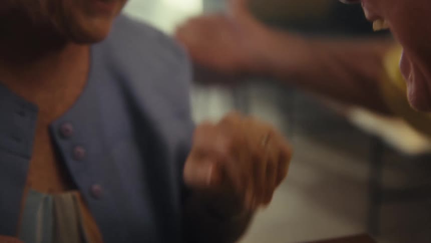 Elderly man hugs an elderly woman after kissing her hand while the two smile happily at each other