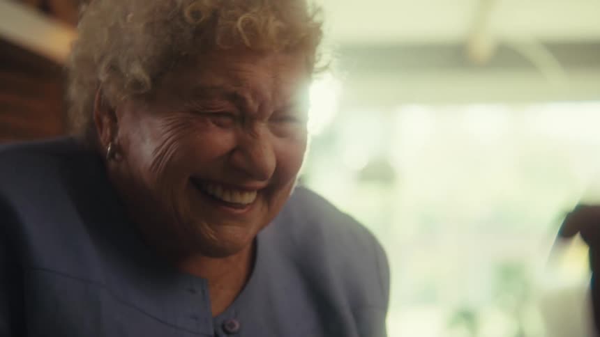 An elderly woman suddenly becomes excited during a discussion indoors