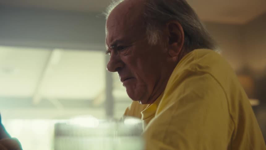 An elderly man sitting looking surprised and annoyed by something