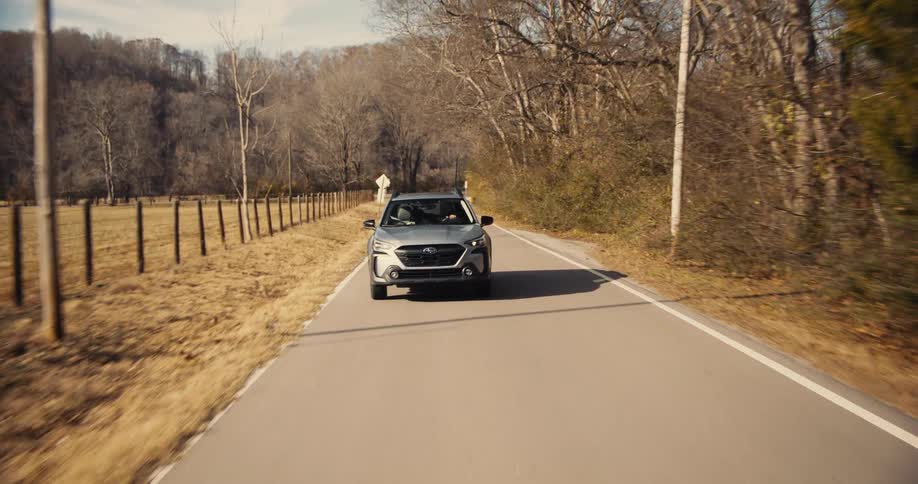 Car driving along a narrow road surrounded by autumn trees