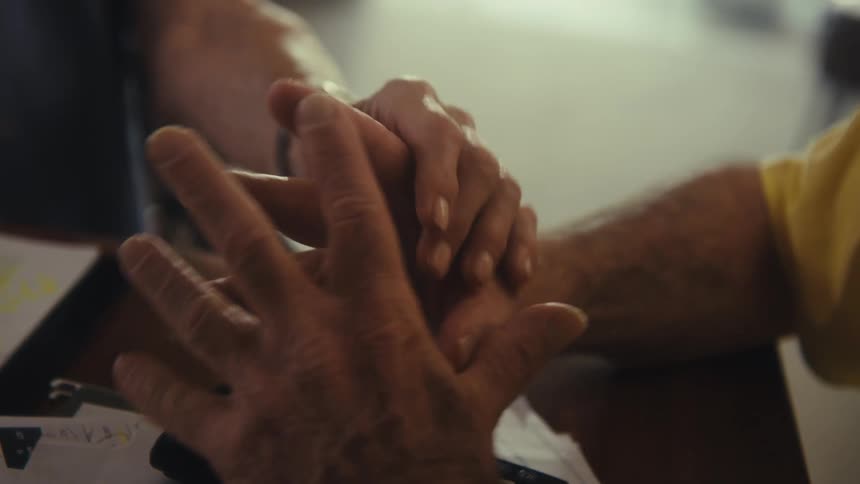 Two hands intertwined on a table conveying support and connection