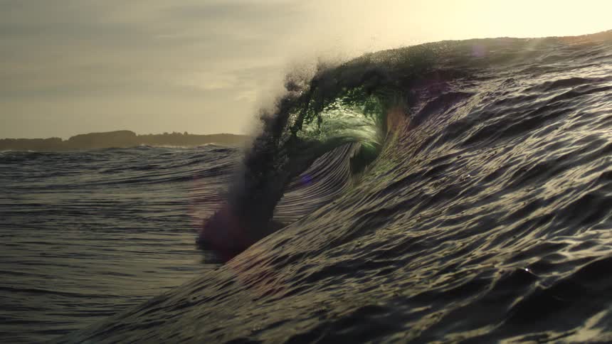 The sun reflects on the large wave