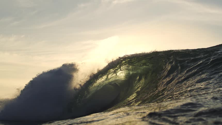 A crashing ocean wave rolls under the dusk sky