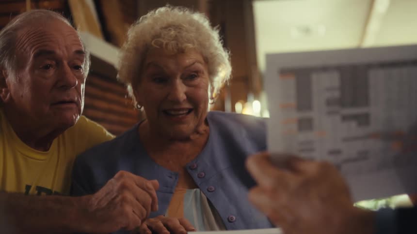 Elderly couple eagerly looking at a spreadsheet shown by someone else