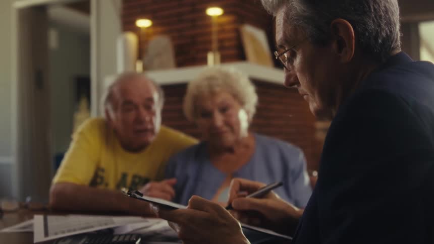 A man fills out a form while talking with a couple