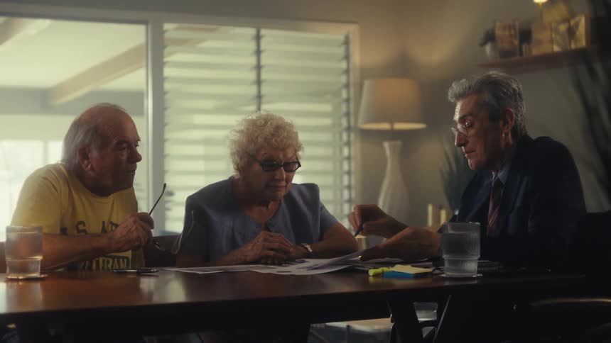 Elderly couple talks with a man in a suit while reviewing documents on the table