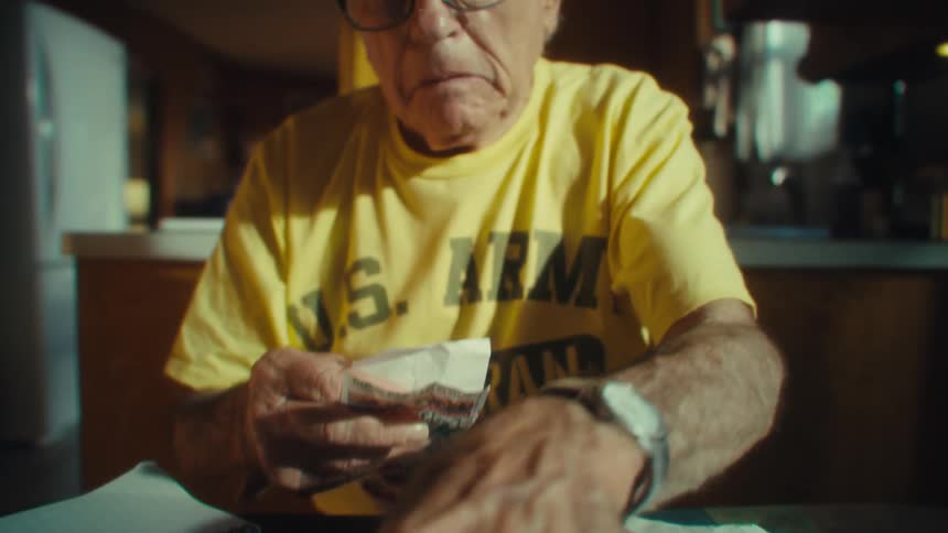 The man is checking a table full of receipts