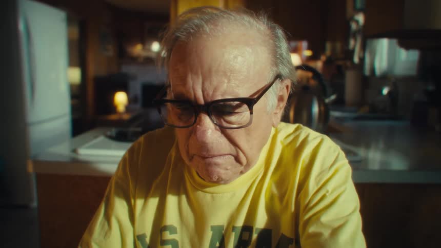 Elderly man wearing glasses with a serious expression
