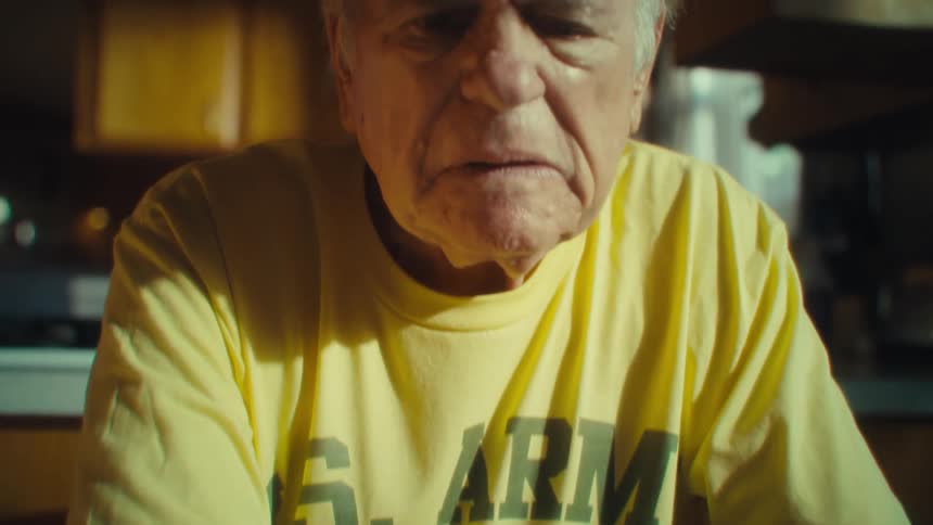Elderly man holding notes sitting at a table