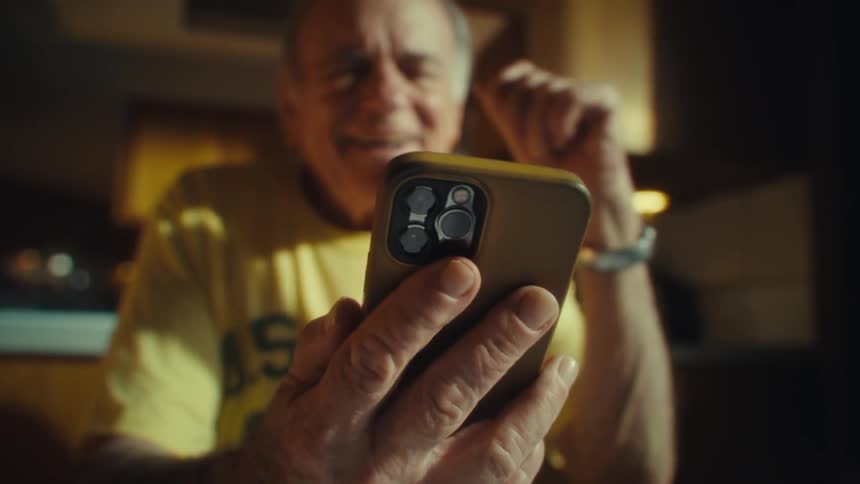 An elderly man talking on the phone with someone and laughing