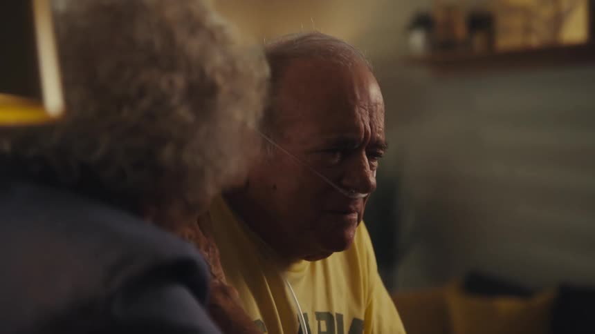 Elderly man is moved as he is comforted by a doctor next to a woman