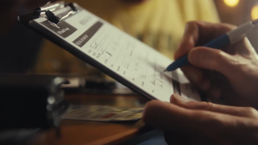 A person fills out a form on the clipboard