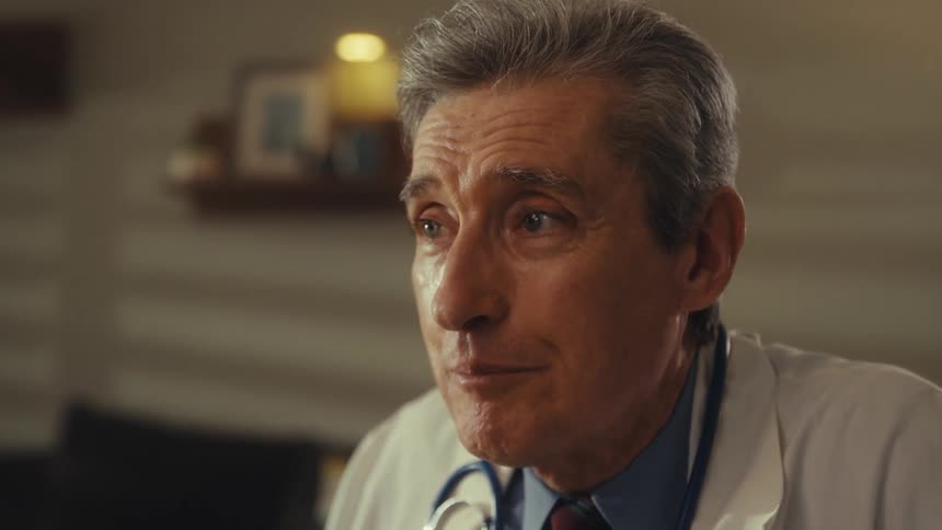 A closeup of a elderly doctor with a stethoscope as he talks and gestures with his hands
