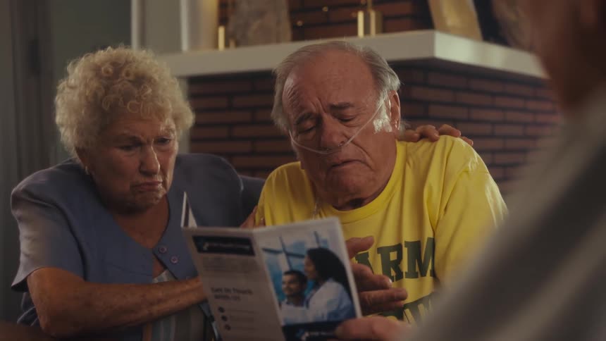 An elderly man on oxygen cries about the contents of a brochure that his wife and another man are showing him