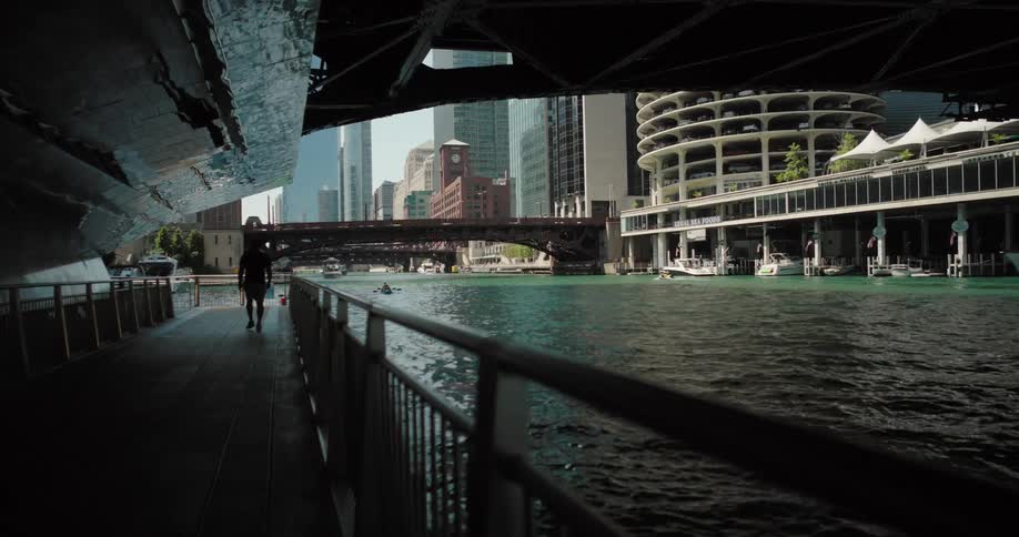 Pedestrians walking across a bridge along a sea canal in a modern metropolis