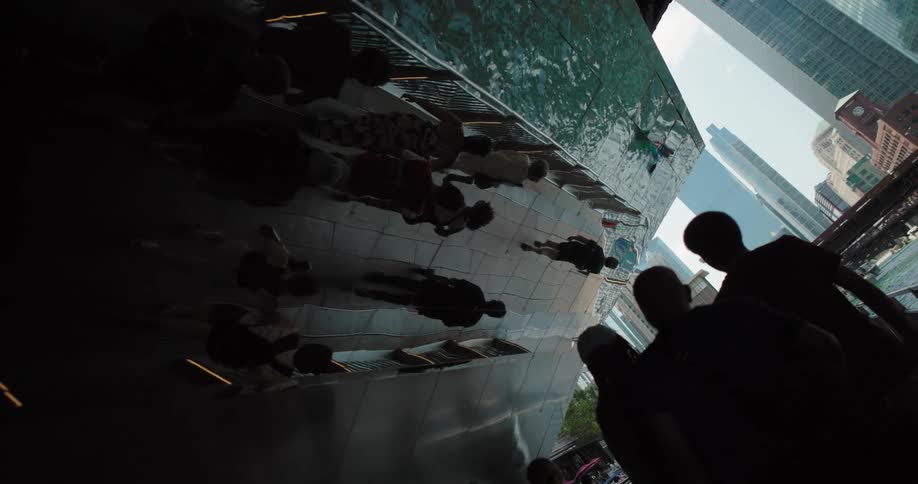 Reflection of people walking on a mirrored wall with skyscrapers in the background