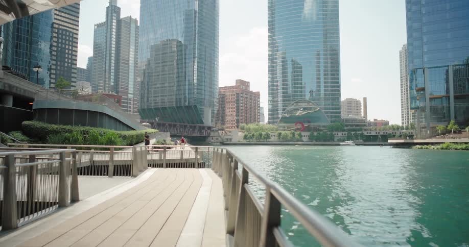 A group of people hanging out under an overpass above a river with a walkway then leading towards a tower block