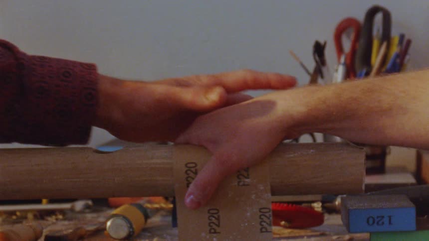 Two hands sand wood in a workshop