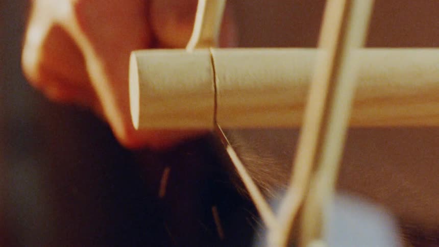 A carpenter is sawing a piece of wood inside a carpentry workshop