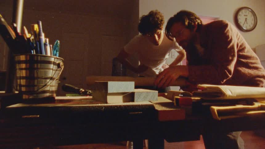 Two men are working together on a carpentry project in a workshop
