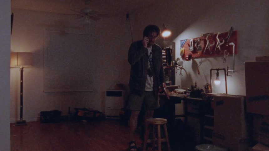 A man standing in a room talking to someone on the phone