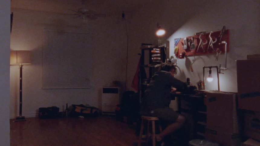 Man sitting on a stool working in an indoor space with tools
