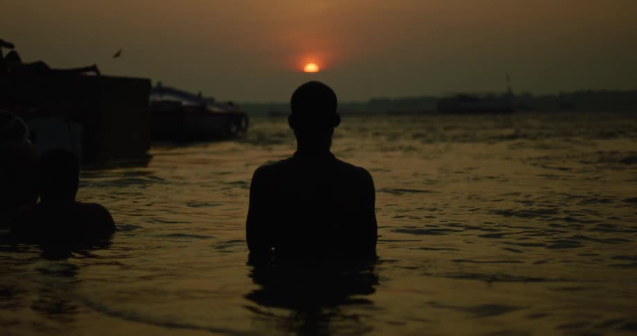 A person is watching the sunrise while standing in the water