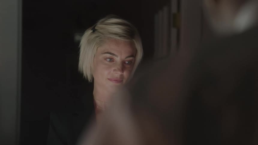 Excited blonde woman in an indoor setting with a silhouette of a person in front of her