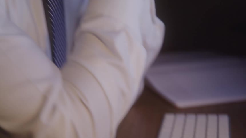 A man feels exhausted from work while typing on a keyboard